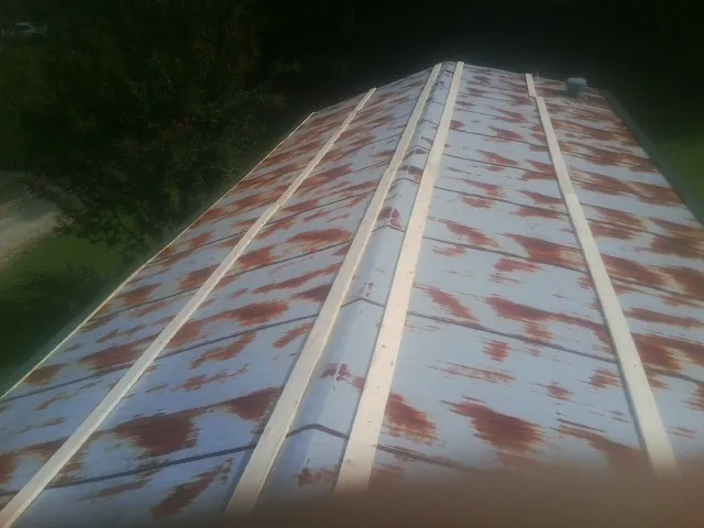 Rusted metal roof panels with new wood purlins before replacement — Storm Damage Roof Repair in Maple City by Roofing Brothers