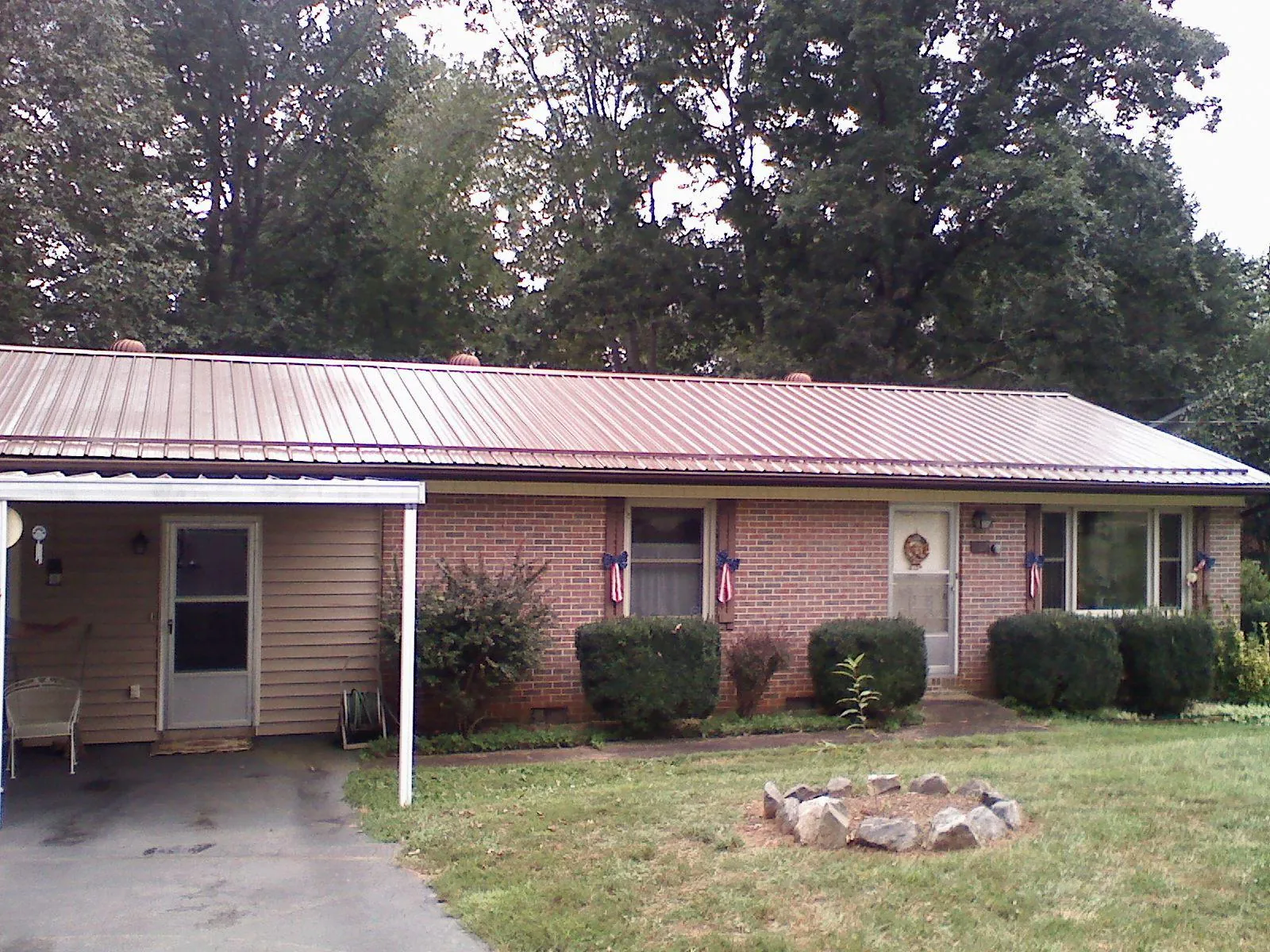 Bronze metal roof and carport on a brick ranch home — Roof Repair work by our crew in Maple City